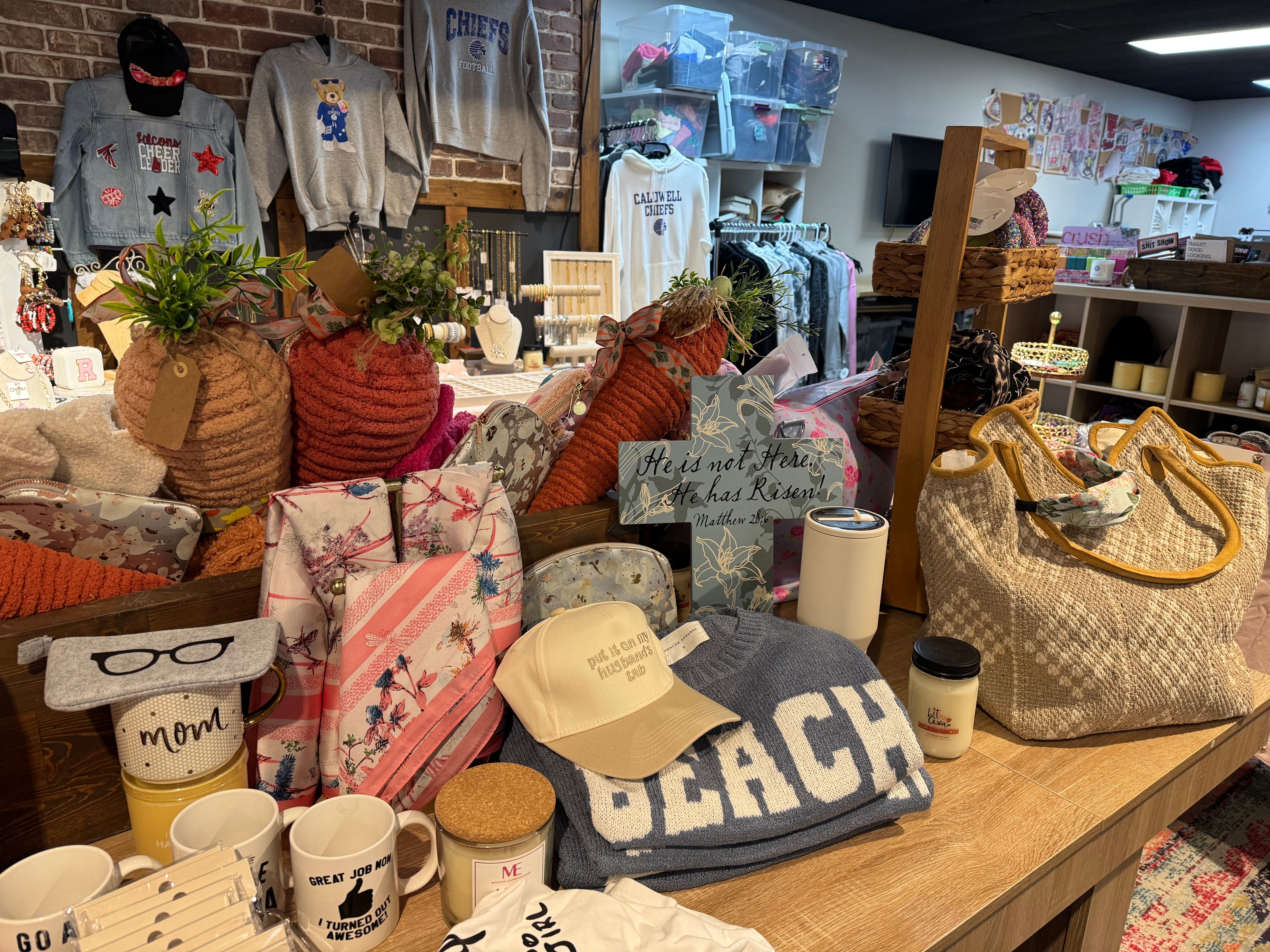 Display of various items including a 'Beach' towel, hats, and bags in a store setting.